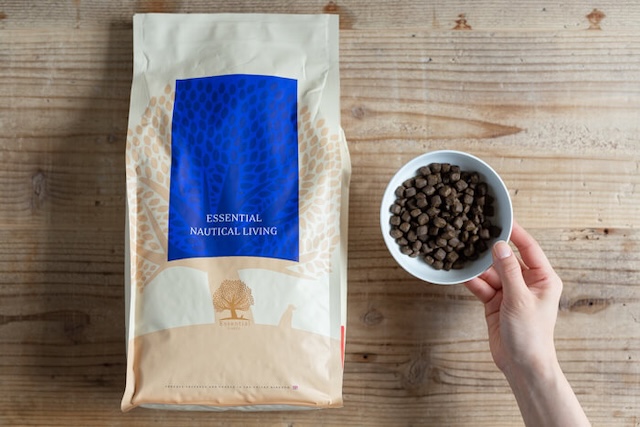 エッセンシャルドッグフードと容器を持つ人の手